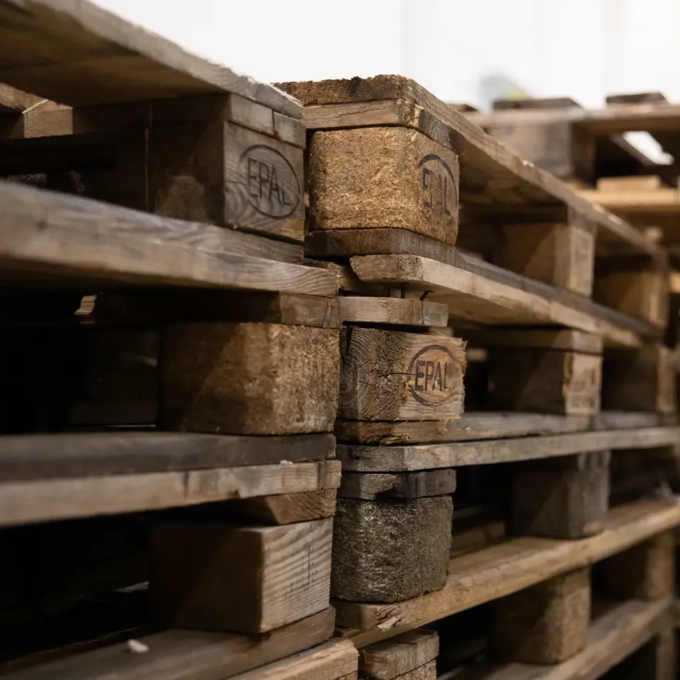 Nahaufnahme gestapelter Holzpaletten mit sichtbarer Abnutzung und EPAL-Markierungen, im Innenbereich mit sanfter Beleuchtung.